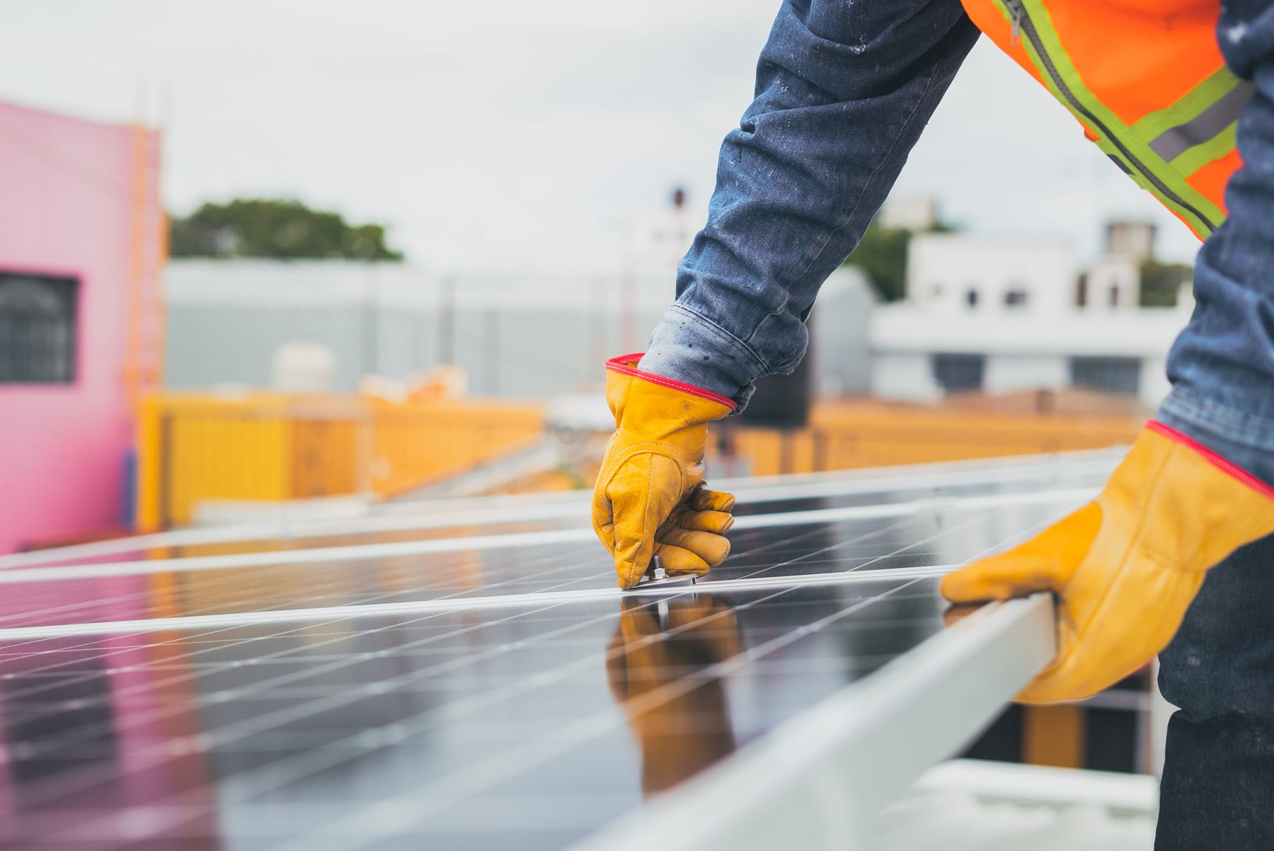 Dois instaladores a montar um painel solar numa estrutura de telhado, de manhã.